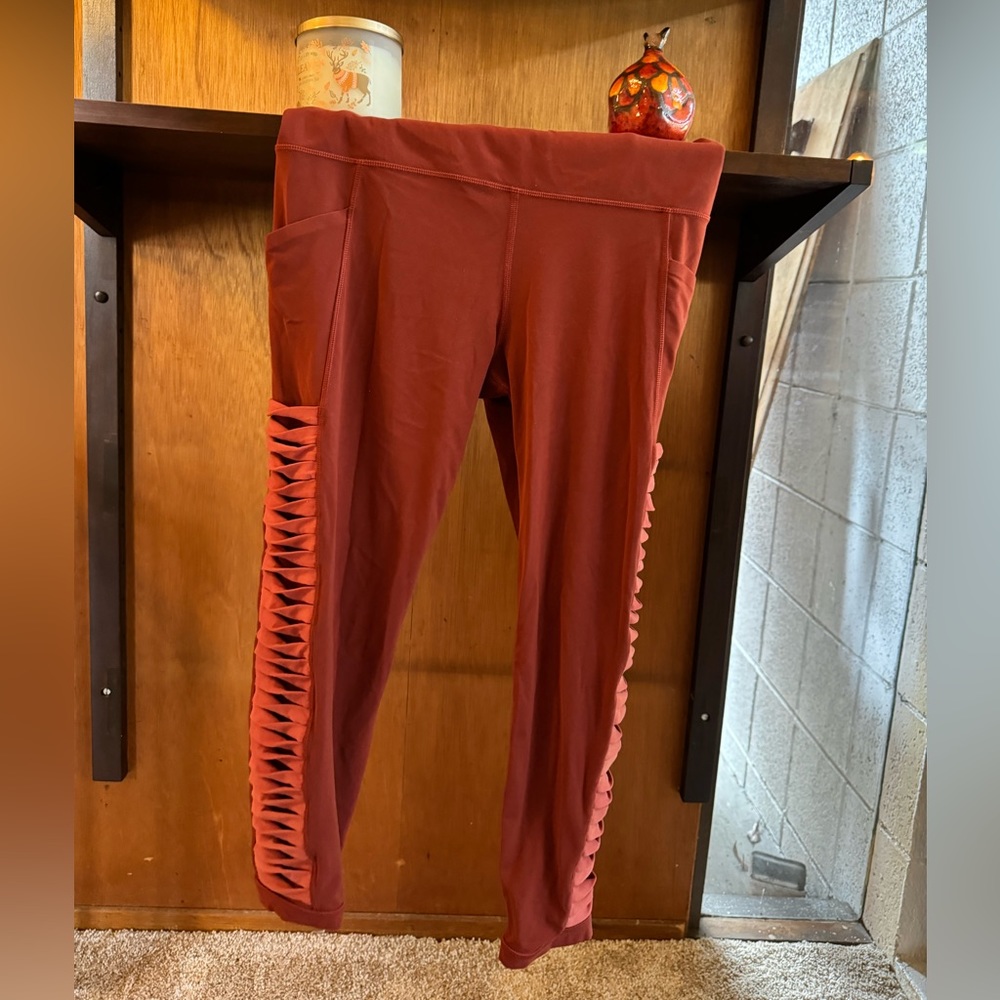 Athleta rust-colored 3/4 leggings with pockets and twist detail on sides